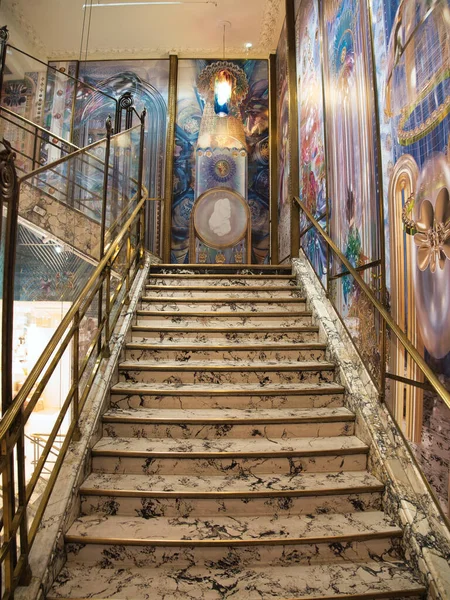 Sanatsal Duvar Resimli Görkemli Mermer Merdiven - Büyük iç merdiven, parlak siyah ve beyaz mermer basamaklar, yaldızlı korkuluklar, ve renkli, detaylı duvar resimleri, muhtemelen Paris 'teki bir mağazanın içinde..