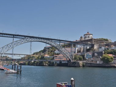 Dom Lus I Bridge ve Porto Skyline Sunset 'te - Douro Nehri' ni kaplayan ikonik metal kemer köprüsünün yüksek açılı görüntüsü, yayalar ve tarihi Porto silueti ve yumuşak akşam ışığında anıtlar.