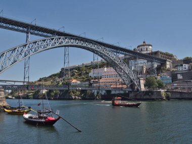 Dom Lus I Bridge ve Porto Skyline Sunset 'te - Douro Nehri' ni kaplayan ikonik metal kemer köprüsünün yüksek açılı görüntüsü, yayalar ve tarihi Porto silueti ve yumuşak akşam ışığında anıtlar.