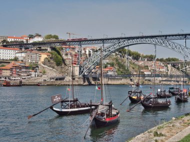 Dom Lus I Bridge ve Porto Skyline Sunset 'te - Douro Nehri' ni kaplayan ikonik metal kemer köprüsünün yüksek açılı görüntüsü, yayalar ve tarihi Porto silueti ve yumuşak akşam ışığında anıtlar.