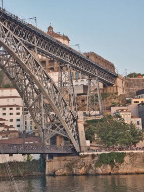 Dom Lus I Bridge ve Porto Skyline Sunset 'te - Douro Nehri boyunca uzanan ikonik metal kemer köprüsünün yüksek açılı görüntüsü, yayalar ve tarihi Porto silueti ve yumuşak akşam ışığında anıtlar.