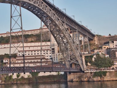 Dom Lus I Bridge ve Porto Skyline Sunset 'te - Douro Nehri boyunca uzanan ikonik metal kemer köprüsünün yüksek açılı görüntüsü, yayalar ve tarihi Porto silueti ve yumuşak akşam ışığında anıtlar.