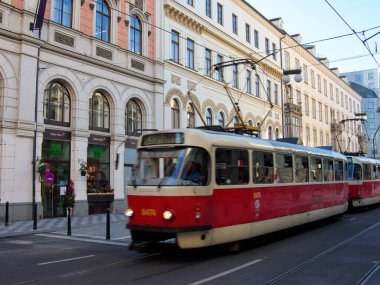 Avrupa Tramvayı - Eski bir kırmızı ve bej tramvay, Orta Avrupa 'nın işlek bir caddesinde gün boyunca süslü tarihi binaların önünden hızla geçti.
