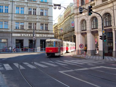 Kızıl Tramvay Sunny Prag Caddesinde Dönüyor - Klasik kırmızı tramvay tarihi binaların önünden geçiyor, günlük şehir yaşamını yakalıyor ve seyahat ediyor.