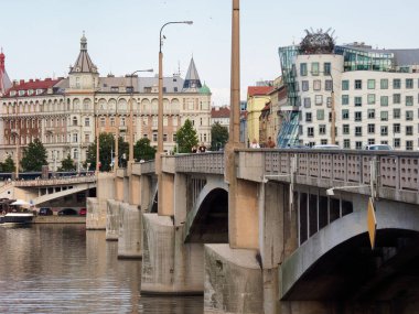 Prag Köprüsü Dans Evi & Vltava Manzarası - Bir köprü ve nehir boyunca uzanan tarihi ve yapısalcı mimari arasındaki kontrastı gösteren şehir sahnesi.