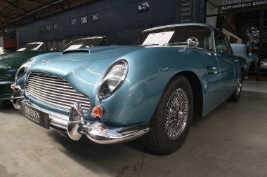 Iconic Classic British GT Car Front - Krom ızgarası ve zarif kablo lastikleri olan ikonik mavi bir İngiliz klasik arabasının ön görüntüsü.