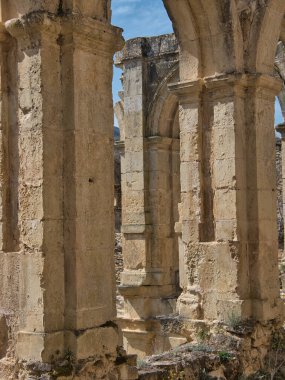 Manastır harabelerinin dokulu taş sütunları - İspanyol manastırının harabelerinde eski, yıpranmış taş sütunların ve Gotik kemerlerin dikey görüntüsü.