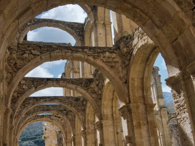 Ortaçağ Manastırı 'nın Kemerleri - Dağlık bir İspanyol manzarasında yer alan mavi gökyüzüne karşı terkedilmiş Gotik bir manastırın taş kemerleri ve kolonları.