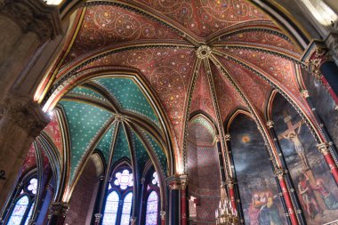 Gotik Kasalar ve Sainte-Chapelle 'in Duvar resimleri - Kırmızı, altın ve deniz mavisi kemerlerle boyanmış Gotik kaburgaların alçak açılı görüntüsü, büyük bir çarmıha gerilme duvar resminin ve vitray pencerelerin yanı sıra.