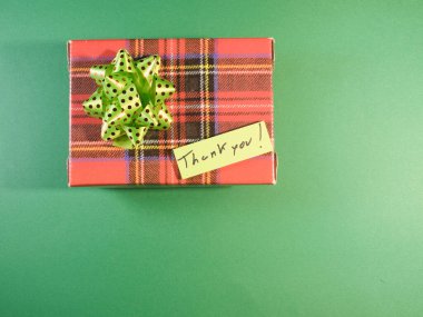 Yeşil noktalı kırmızı bir ekoseli hediye kutusundan yeşil benekli bir fiyonk ve bir 