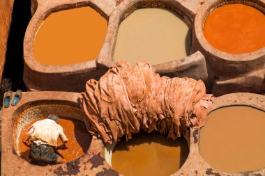 Fez-Fez-Mequinez-Marruecos-20 Ağustos 2016, Fas 'ın Fez el-Bali kentindeki ünlü Chouara Tannery' nin renkli taş fıçılarında bir zanaatkar saklanıyor. Bu antik deri üretim yöntemi yüzyıllar öncesine dayanıyor..