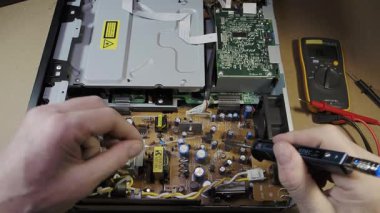 PCB 'deki lehimleme bileşenleri - Teknisyenin elleri modern bir tüketici cihazını tamir etmek için lehimleme demiriyle elektronik devre kartını tamir ediyor.