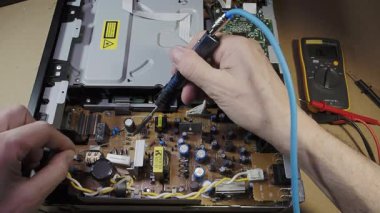 PCB 'deki lehimleme bileşenleri - Teknisyenin elleri modern bir tüketici cihazını tamir etmek için lehimleme demiriyle elektronik devre kartını tamir ediyor.