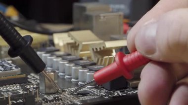 Çokölçer ile Elektronik Onarım ve Bakım Bir DVD oynatıcısının veya benzer bir cihazın devre kartındaki voltajı kontrol eden bir teknisyenin elleri.