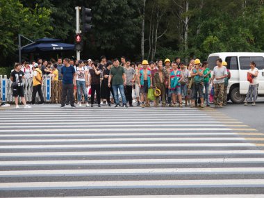 Pekin-Pekin-Çin-18 Ağustos 2018 'de, aralarında sıkı şapka ve güvenlik yelekleri giyen göçmen işçilerin de bulunduğu yoğun bir yaya topluluğu, Çin' in işlek bir kentsel bölgesinde işlek bir caddeyi geçmek için bekliyor..