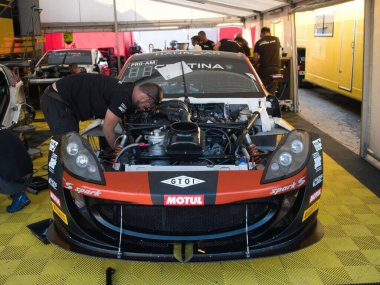 Barselona-Katalonya-İspanya-29 Eylül 2018 bir yarış ekibi teknisyeni Hankook, Certina ve Motul sponsorluğunda kapalı otoparkın içinde korunmasız bir yarış arabası üzerinde çalışıyor..