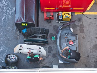 Barselona-Katalonya-İspanya-29 Eylül 2018, yarış takımının mekaniğinin yüksek açılı görüntüsü karbon fiber kaporta ve bir Blancpain GT serisi yarış arabasının bileşenleri üzerinde bakım ve onarım yapıyor..