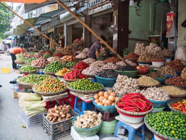 Hanoi-Vietnam-10 Ağustos 2019, Vietnam 'da kalabalık bir market tezgahına yığılmış sarımsak, biber, limon ve kök dolu sepetler yerel aşçılık geleneğini yansıtıyor..