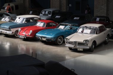 BERLIN-Almanya-16 Nisan 2025, aralarında Porsche 356, Corvette C2 ve Alfa Romeo 2600 'ün de bulunduğu çeşitli klasik otomobiller Berlin, Almanya' da bir klasik otomobil galerisinde sergilendi..
