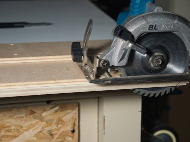 Dairesel Testere Bıçağı Kesen Plywood 'un yakın çekimi, bir tezgahta kontrplağı kesen güçlü el yapımı dairesel testere bıçağının detaylı görüntüsü. DIY ve inşaat işleri için gerekli güç aracı.