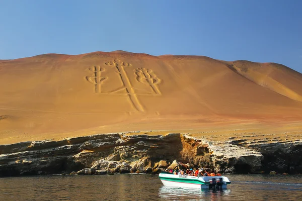 Paracas, Peru-26 januari: ongeïdentificeerde mensen kijken naar Candelabra van de Andes vanaf een boot op 26 januari 2015 in Pisco Bay, Peru. Candelabra is een bekende prehistorische geoglyph die gevonden wordt op het noordelijke gezicht van het schiereiland Paracas — Stockfoto