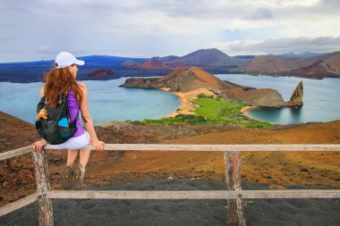 Young woman enjoying the view of Pinnacle Rock on Bartolome isla clipart