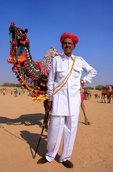 Hombre indio de pie con su camello decorado en el Desert Festival , — Foto de Stock