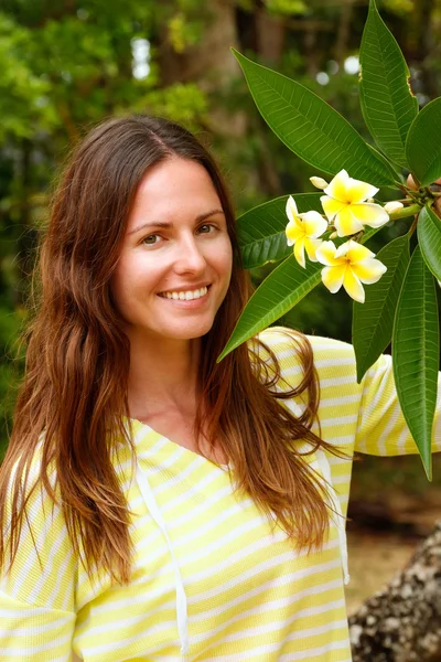 Plumeria ağacın yanında duran genç kadın — Stok fotoğraf