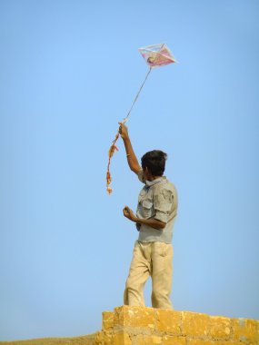 Bu geleneksel evinde çatıdan uçurtma uçan Hintli çocuk