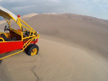 Dune buggy at the top of steep hill in a desert near Huacachina, clipart