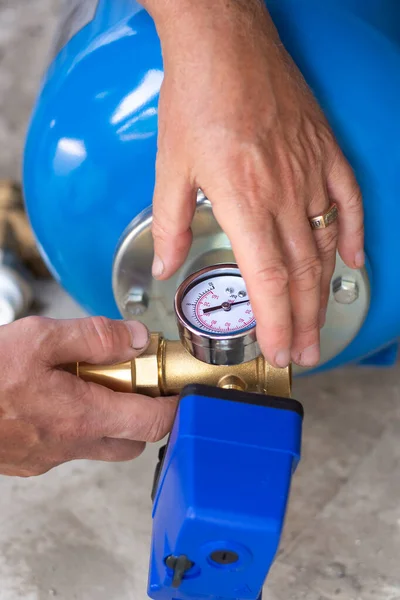 Pumping station for water supply of a residential building, the master installs a hydraulic accumulator — Stock Image Pumping station for water supply of a residential building, the master installs a hydraulic accumulator Royalty Free Stock Photos