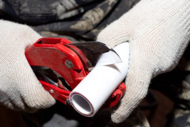 Tesisatçı tesisat tesisatı için polipropilen borusunu kesiyor..