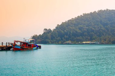 Koh Chang. Tayland-01.18.2020: Tayland parlayan teknesi denizdeki iskelede, yeşil dağların arka planına karşı, sudan manzaralı. Asya 'da seyahat ve turizm