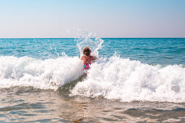 little girl in the sea wave. The child is swimming in the sea. Summer vacation and vacation on the coast in Russia. Safety in the water