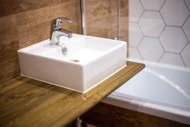 Banyo tasarımı. Ahşap desenli duvar panelleri. Karıştırıcılı kare bir lavabo rafta duruyor..