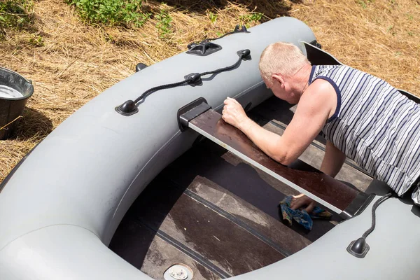 A man washes a rubber boat at home in the garden. Caring for rubber vehicles. Swimming device operation