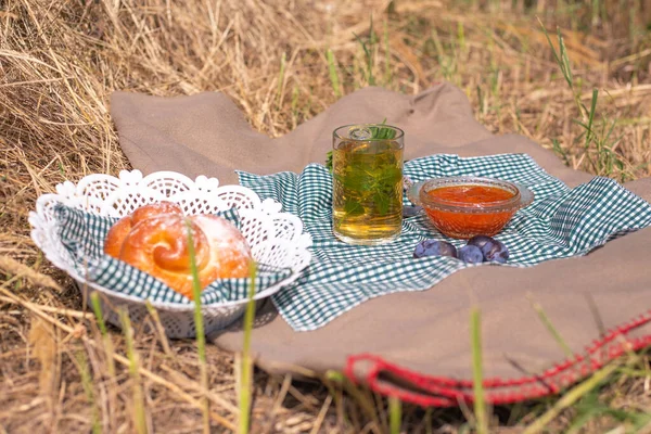 Picnic on the grass. Autumn tea with mint and berry jam for breakfast on dry grass. Outdoor recreation concept.