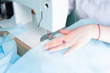 Kadın dikiş makinesine dikiş dikiyor, elle dikiş dikiyor, dikiş dikiyor, ev ödevi yapıyor.