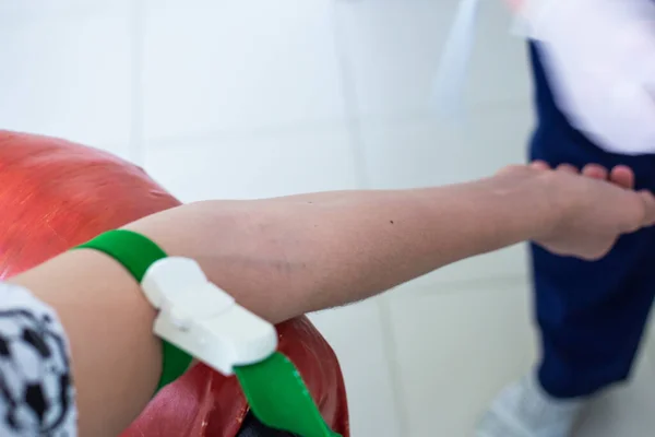 the patient hand is tightened with a medical tourniquet, the nurse is preparing for blood sampling for analysis in the treatment room, coronavirus diagnosis