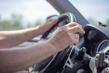 Bir adam araba kullanıyor, elleri direksiyonda, içi araba dolu, seçici odaklı.