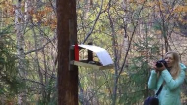 Orman fotoğraflarında elinde kamera olan ceketli bir kadın. 