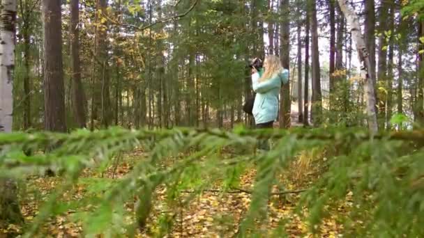 Kobieta spaceruje w jesiennym lesie i robi zdjęcia natury — Wideo stockowe