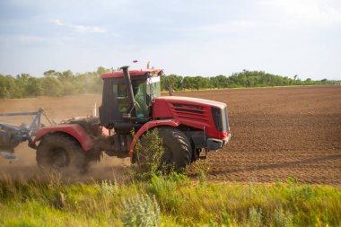 Traktör ekin için toprağı sürüyor, güneşli bir günde sabanla, tarımla.
