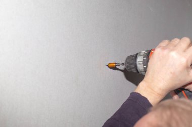 Adamın biri alçıpana vida takmak için tornavida kullanıyor. Ev onarımı, duvar kaplaması..