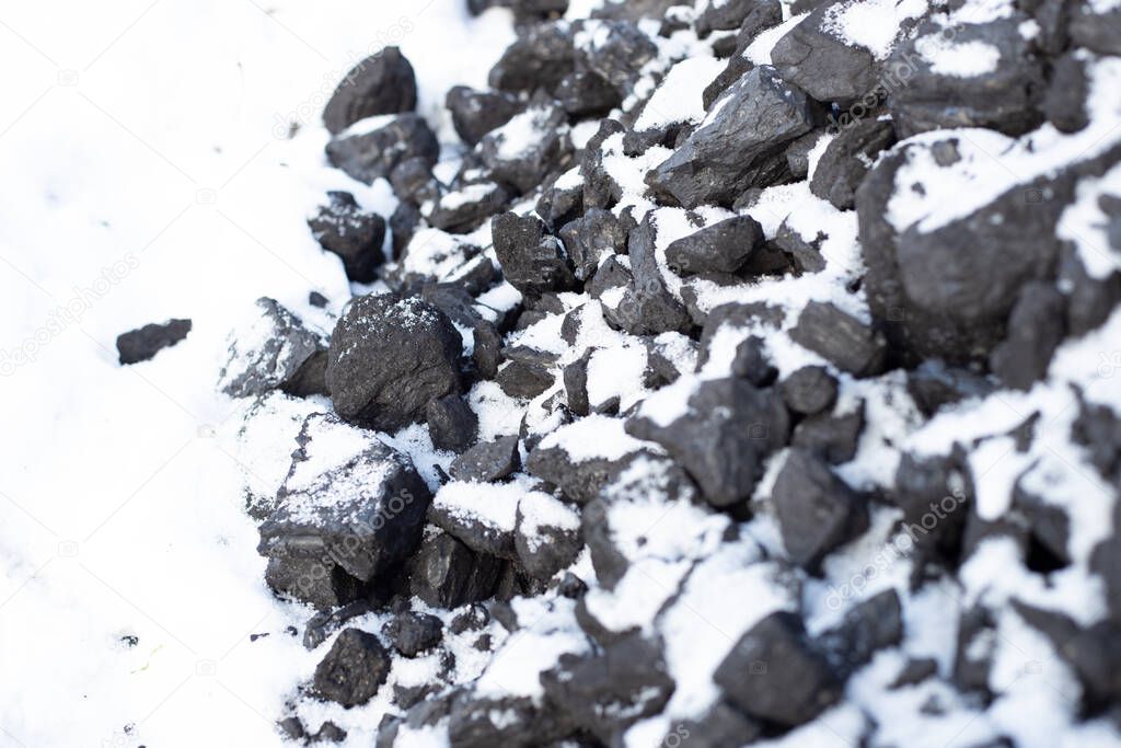 large pieces of coal under the snow. Fuel for the stove in winter. Heating a house in the countryside.
