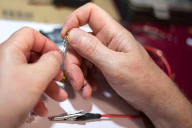 Bir adam elinde tuttuğu LED 'i tamir ediyor.