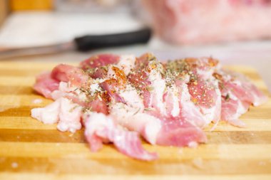 Kesme tahtasına çiğ et serpiştirilmiş, baharat serpiştirilmiş, bıçağın yanında, seçici bir odak noktası.