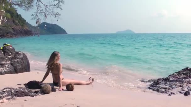 Meisje in bikini zit op het strand op het zand — Stockvideo