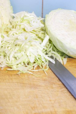 Tuz ve salata için doğranmış beyaz lahana, tahta bir tahta üzerinde, bir bıçakla, kopyalama alanı