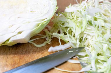 Tahtanın üzerinde, bıçağın yanında doğranmış taze lahana.